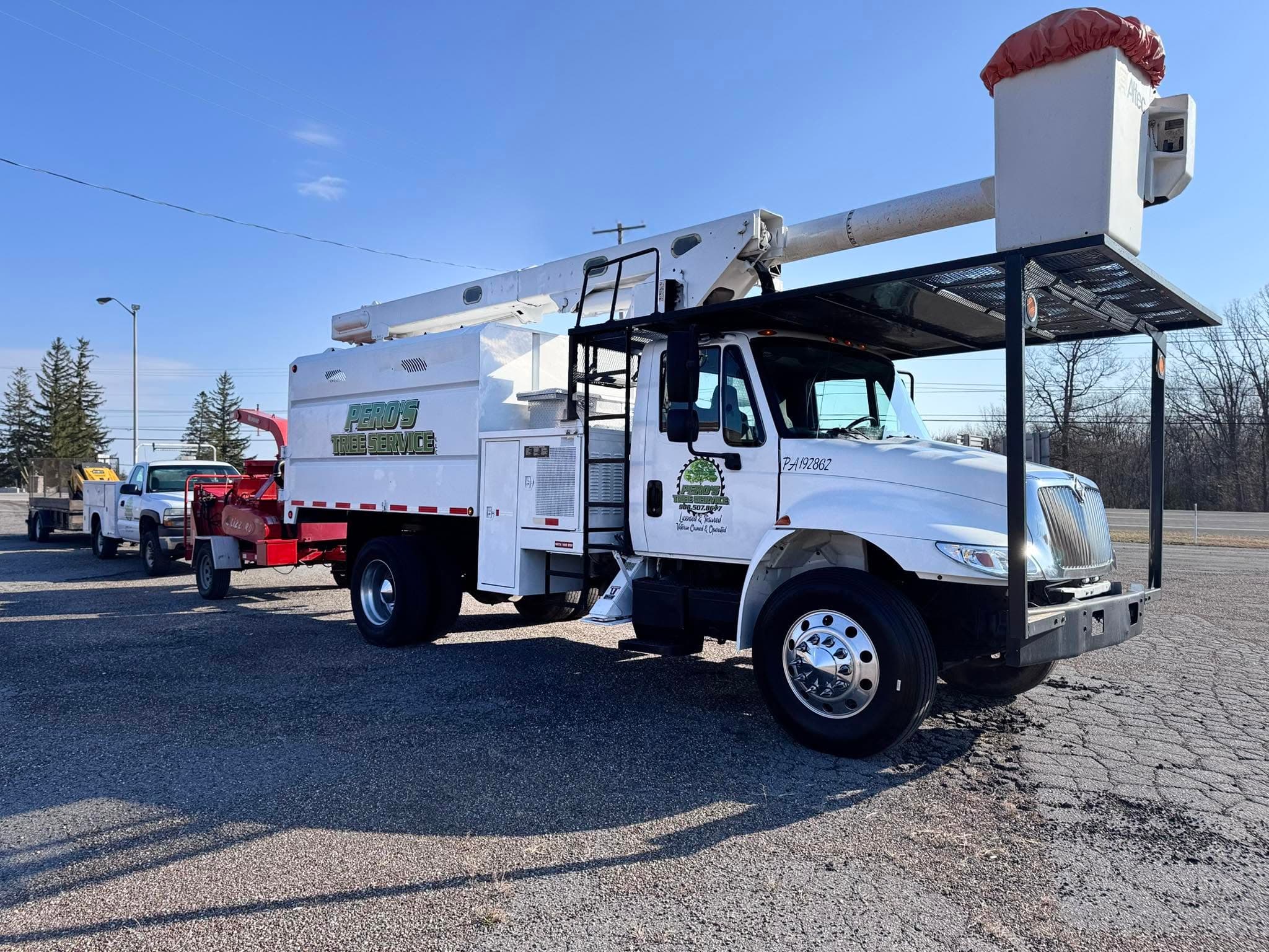 Peros Tree Service bucket truck and wood chipper parked and ready for a job
